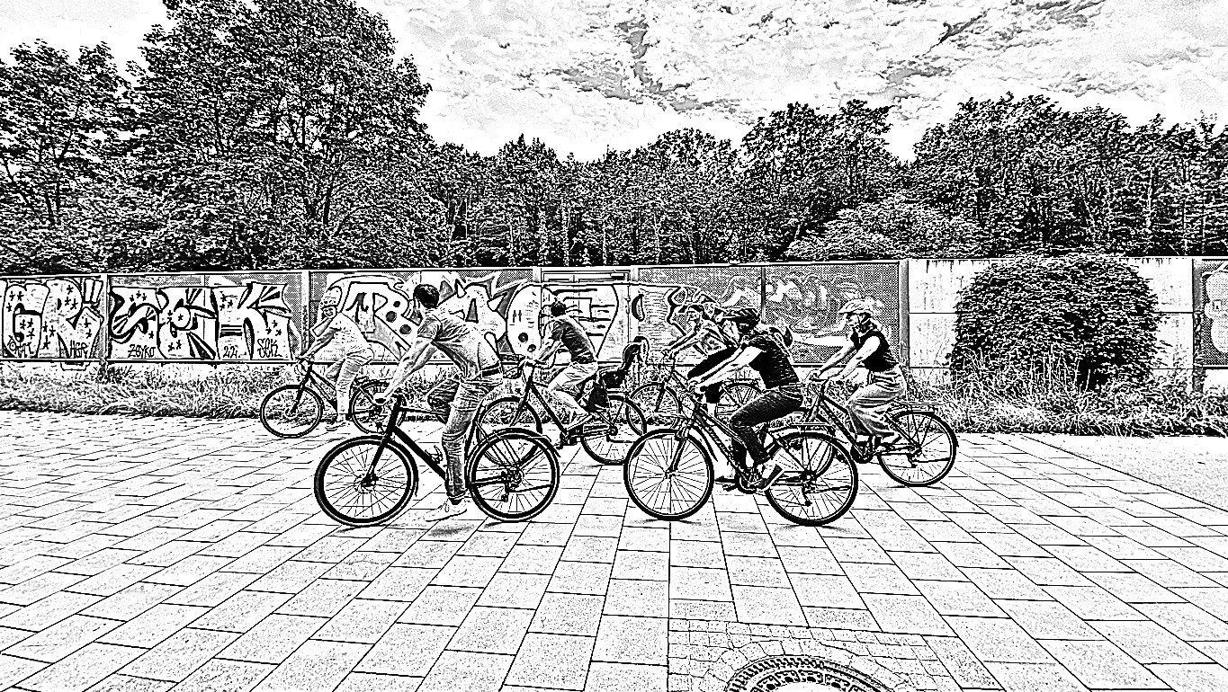 Sechs Personen fahren Fahrrad vor einer Wand mit Graffiti